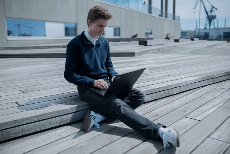 Ung mand arbejder på en Lenovo bærbar computer på en træterrasse