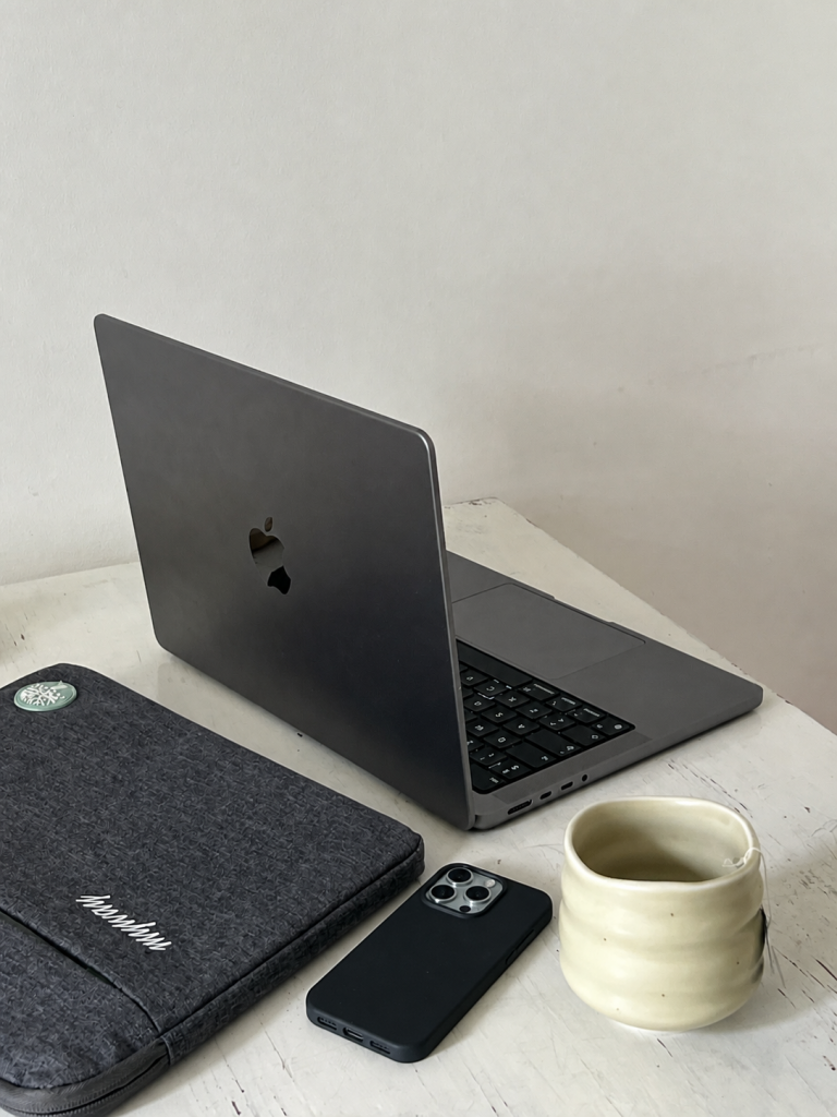 iphone 15 pro ligger på bord med computer og kop